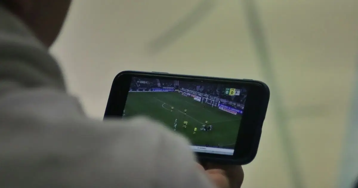A person watching a football match on a phone held in landscape