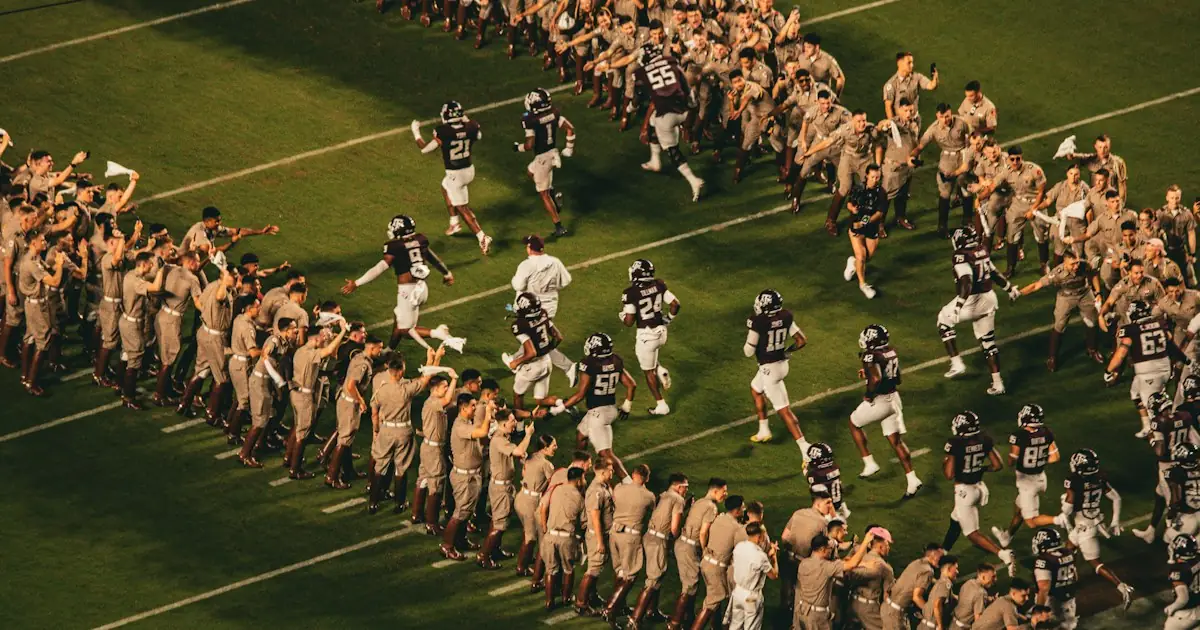 Players running out between rows of cheering fans