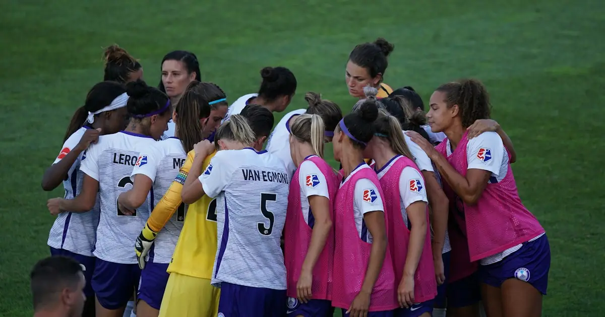 A women’s football team in a tight huddle