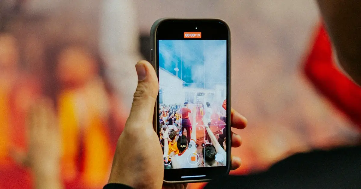 A fan filming the match on a phone in the stands